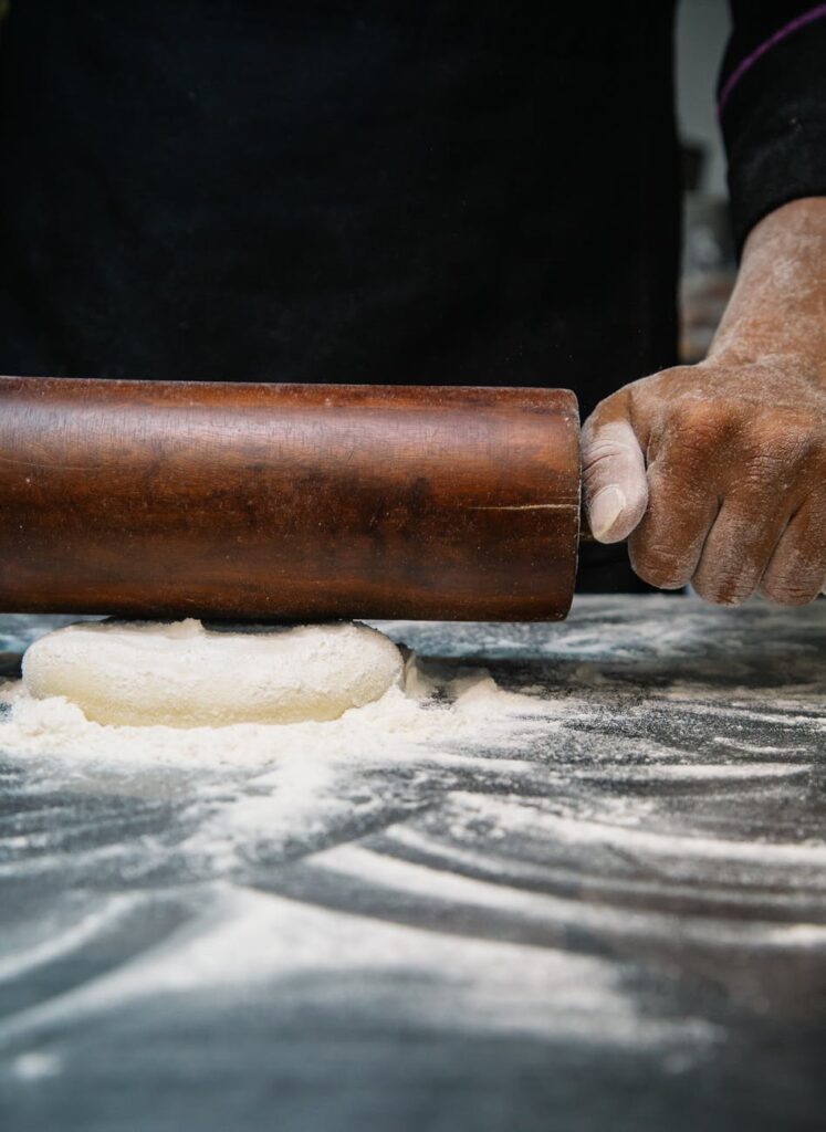 person using brown wooden rolling pin