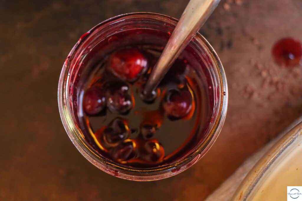 This is a picture of brandied cherries in a mason jar, with a spoon.