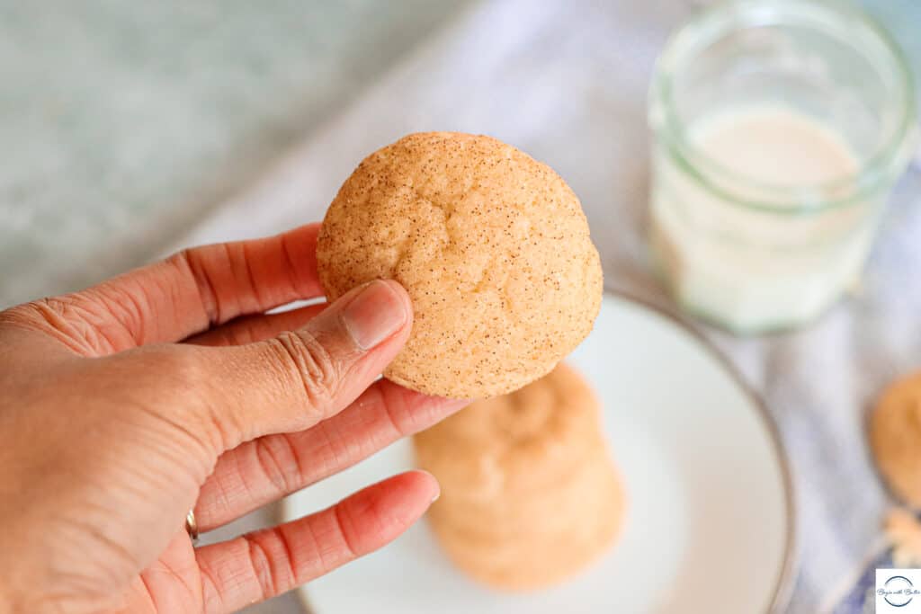 This is a picture of my hand in front of a plate of snickerdoodle cookies.