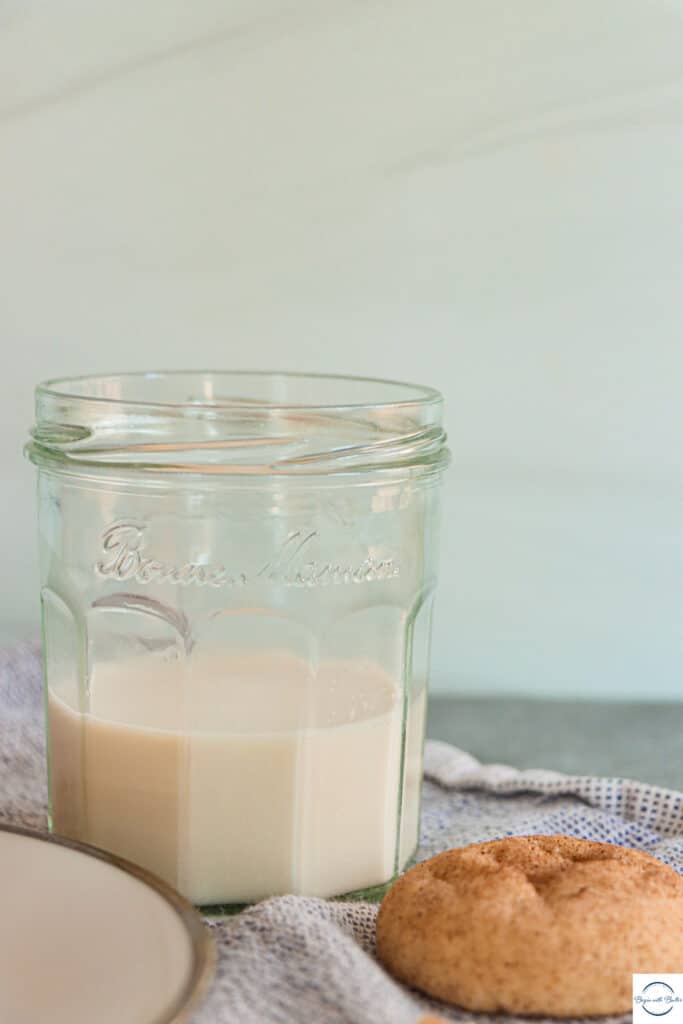 This is a picture of a snickerdoodle cookie in front of a glass of milk.